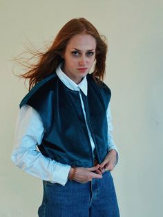 a woman with red hair wearing a blue vest