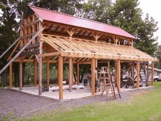 a large wooden structure with metal roof and ladders on the ground next to it