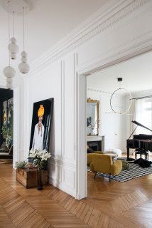 a living room filled with lots of furniture and paintings on the wall next to a piano