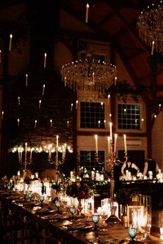 a long table with many lit candles and place settings in front of a large window