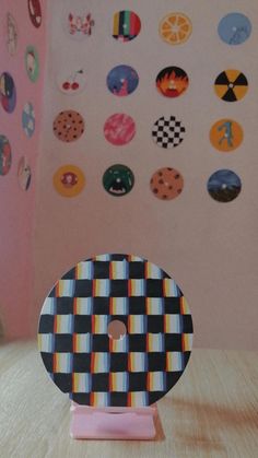 a wooden table topped with a black and white checkered plate next to a pink wall