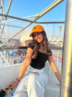 a woman sitting on top of a metal pole next to a sky scraper at an amusement park