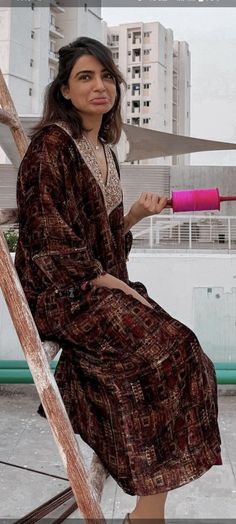 a woman sitting on top of a wooden ladder holding a pink object in her hand