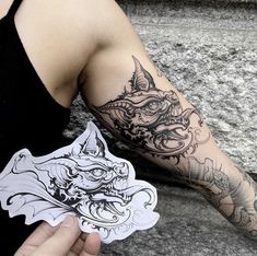 a person holding up a sticker with a dragon on it's left arm