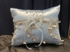 a light blue pillow with white flowers on it and a ribbon tied around the edge