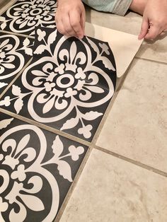 a person is cutting out decorative tiles on the floor