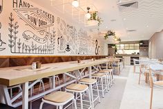 an empty restaurant with tables and stools in front of a wall painted with black and white graphics