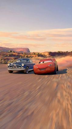 two cars driving down a dirt road in front of a desert landscape with mountains and clouds