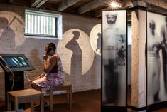 a woman sitting on a bench in front of two display cases with images behind her