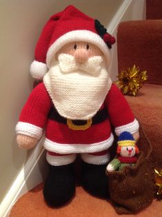 a knitted santa clause doll next to a christmas decoration on the stairs in a home