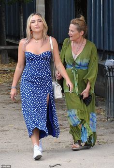 two women are walking down the street together, one is wearing a blue and green dress