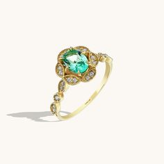 a gold ring with an oval green stone surrounded by small white and clear diamonds on the band