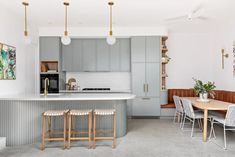 a kitchen with gray cabinets and wooden stools next to an island counter top in the middle