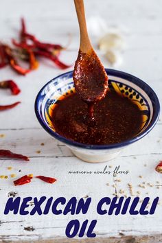 a spoon full of chili sauce on top of a white table with red peppers scattered around it