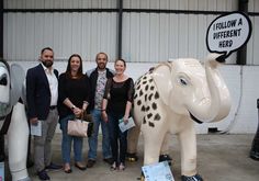 four people standing in front of an elephant statue with a sign that says follow a different hero