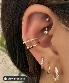 a woman with three different ear piercings on her left ear and one is wearing a gold ring