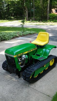 a small green tractor parked on the side of a road in front of some trees