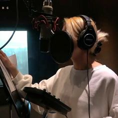 a woman wearing headphones is reading a book in front of a microphone and recording equipment