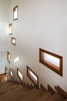 there are many windows on the wall above the stairs in this house that is made of wood