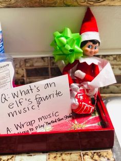 an elf is sitting on top of a music box with a note attached to it