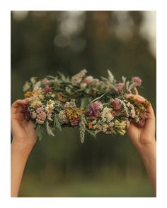 two hands holding flowers in the middle of each other's hands, with trees in the background