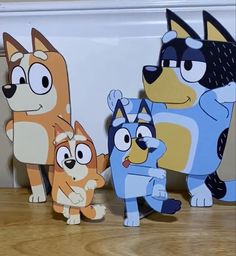 three cardboard cut outs of cartoon characters standing next to each other on a wooden floor