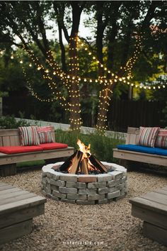 Cozy outdoor fire pit surrounded by wooden benches with colorful cushions, and trees adorned with string lights.