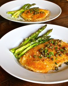 two white plates topped with fish and asparagus