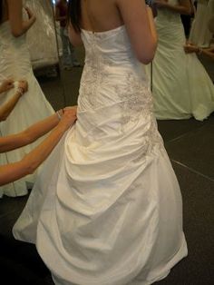 a woman in a white wedding dress looking at herself in the mirror with her reflection