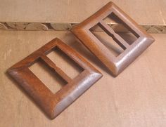 two wooden square shaped objects sitting on top of a brown floor next to each other