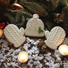 two heart shaped cookies sitting on top of snow next to candles