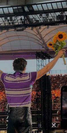 a man standing on top of a stage holding a bouquet of flowers in his hand