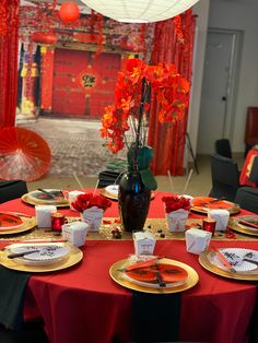 a table with plates, cups and vases on it in front of red curtains