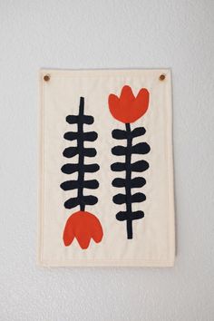 a white wall hanging with black and red designs