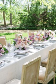 the table is set with white linens, pink flowers and silverware for dinner