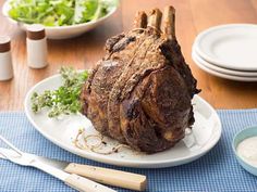 a large piece of meat sitting on top of a white plate next to a salad