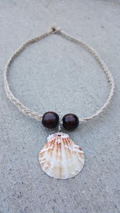 A brown, cream, and white seashell and dark red wood beads on braided cream hemp string. Drilling, twisting, and braiding is done by hand. White Waxed Cord Beach Jewelry, White Waxed Cord Jewelry For Beach, Handmade Adjustable Natural Shell, Bohemian Brown Shell As Gift, White Waxed Cord Jewelry For The Beach, Adjustable Brown Shell For Beach, Brown Waxed Cord Beach Necklaces, Cream Shell Necklace For Beach, Adjustable Cream Shell Necklace For Beach