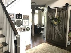 an entryway with stairs and pictures on the wall next to a door that has a wreath hanging on it