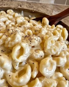 a bowl full of macaroni and cheese with a wooden spoon