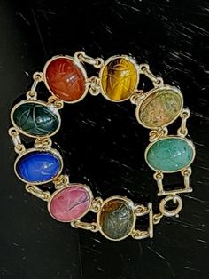 This vintage 14K gold bracelet features a stunning assortment of carved gemstone scarabs in multicolor hues. The double link chain style is secured with a spring ring closure and measures approximately 7.5 inches in length. The 14K yellow gold and assortment of gemstones make this piece a truly unique addition to any jewelry collection. Perfect for fans of Egyptian-inspired jewelry or lovers of vintage finds. There are a few natural inclusions/cosmetic blemishes. Considering its age, it's into perfect condition. Stamped and tested for 14K Gold, total weight, 23 Grams. Please view the photos as they are part of the description. Thank you in advance for your business. Please visit my eBay Store >>>>>>>https://www.ebay.com/str/timelesstreasureartifacts Egyptian Inspired Jewelry, Eclectic Jewelry, Scarab Bracelet, Egyptian Inspired, Egyptian Scarab, Ancient Jewelry, Vintage Eclectic, Fine Jewelry Bracelets, Inspired Jewelry