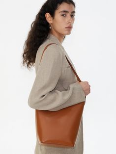 Editor's NotesROWH presents a bucket shopper bag with a timeless design that complements a variety of outfits. - Bucket bag style- Single long top handle- Relaxed silhouette- Inner card slots- Spacious storage- Classic and casual style Measurements(in.)One Size- Size: 10.24 in. (W) * 10.83 in. (H) * 4.72 in. (D)- Strap: 10.24 in. (L) Composition & Care- Material: Shell: 100% Cow Leather, 100% Cotton / Lining: 65% Polyester, 35% Cotton / Strap: 100% Cow Leather- Natural leather may have fine scratches and wrinkles- Bright leather can get stained by denim or dark outfits- Avoid direct heat and moisture- Wipe off moisture and stains with a dry cloth- Natural dry in the shade- Avoid friction to prevent the peel-off from the metal plating- Be cautious when using wet Cognac Shoulder Bag With Handle Drop For Work, Cognac Shoulder Bag For Work, Timeless Brown Top Handle Bucket Bag, Cognac Leather Bucket Bag For Work, Luxury Brown Hobo Bag With Rolled Handles, Modern Cognac Hobo Bag For Formal Occasions, Bucket Shoulder Bag With Handle Drop For Work, Elegant Brown Bucket Bag With Rolled Handles, Cognac Colored Formal Bag For Fall