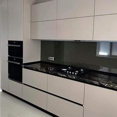 a kitchen with white cabinets and black counter tops in the middle of an empty room