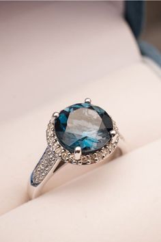 a ring with blue and white stones on it sitting in a box next to some other items