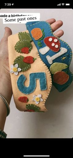 someone is holding two small purses made out of felt and fabric with embroidered letters on them