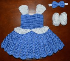 a crocheted blue dress with white trim and matching shoes sits on a table