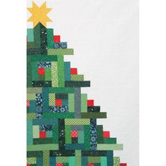 a quilted christmas tree is hanging on the wall next to a white wall with a yellow star above it