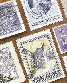 four different stamps on a table with one showing grapes and the other featuring an image of a woman