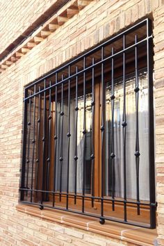 an open window with bars and curtains on the side of a brick building next to a street sign