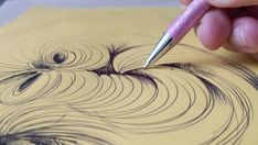 a person drawing with a pen on top of a piece of paper