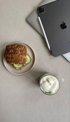 a plate with a sandwich on it next to a glass of yogurt and an ipad